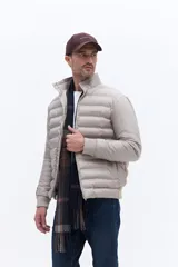 Campera puffer de nylon color beige, con diseño minimalista, cuello alto, cierre frontal y puños elásticos. Presenta logo de la marca bordado en el pecho.