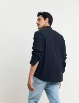 Camisa de cuello mao y manga larga, confeccionada en una mezcla de lino y algodón. Presenta un diseño de corte recto con botones en tono natural y un bolsillo pequeño en el pecho.