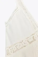 Top blanco de escote pico y tirantes finos, con detalle de encaje a tono y bajo recto.