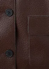 Chaqueta de cuero sintético marrón con cuello camisero, cierre frontal con botones oscuros y bolsillos frontales con solapa.
