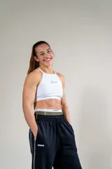 Top deportivo blanco con cuello halter y logo de la marca en el frente.