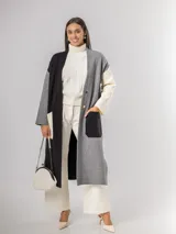 Sacón tipo tapado de corte largo, confeccionado en tejido de punto con diseño color block en tonos gris, negro y blanco. Presenta cierre frontal con botones, bolsillos laterales de parche y aberturas en los costados.