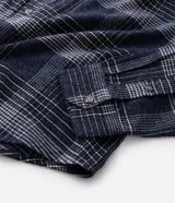 Camisa de manga larga confeccionada en franela de algodón, con cuello bowling y cierre frontal de botones. Presenta un diseño de estampado a cuadros en tonos marrones y beige, con un corte regular tradicional.