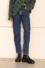 Pantalón de jean azul oscuro, de corte recto y tiro medio, con detalle de ruedo desflecado.