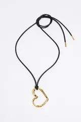Collar largo con cordón negro ajustable y dije de corazón calado con textura irregular en tono dorado.