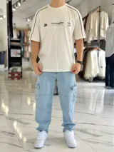 Remera regular color off-white, con diseño gráfico en la espalda que incluye el número 99 en gran tamaño y detalles en negro. Cuenta con ribetes negros en las costuras de los hombros y mangas.