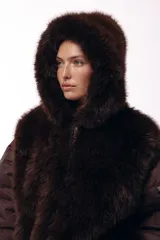 Campera de invierno con frente de piel sintética y capucha integrada, combinada con mangas acolchadas de estilo puffer en color marrón oscuro.