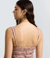 Vestido corto evasê de viscosa con estampado de cuadros vichy en tonos rosado y blanco. Presenta breteles anchos, escote cuadrado, lazo ajustable en el busto y falda con volados.
