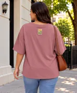 Remera de manga corta color rosado, con diseño oversize, cuello redondo y un pequeño parche estampado en la parte superior de la espalda con motivos florales y la frase "Wild Soul".