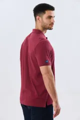 Remera polo lisa de piqué en color bordó, con cuello camisero, cierre frontal con botones y mangas cortas.