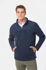 Buzo de micro polar con interior térmico, cuello alto y cierre frontal parcial. Presenta paneles de taslón al tono en el frente y cuello, con bolsillos laterales con cierre y detalle de logo en la manga.