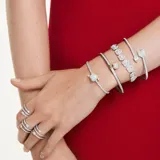 Brazalete rígido con baño de rodio en forma de flecha de Cupido, adornado con cristales transparentes y cierre de bisagra.
