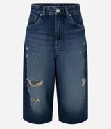 Bermuda tipo jorts de jean azul con talle medio, calce amplio y detalles de roturas y desgaste localizados.