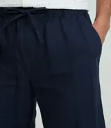 Bermuda recta de playa en color blanco roto, confeccionada en algodón texturizado con efecto de rayas verticales. Posee cintura elástica con cordón ajustable.