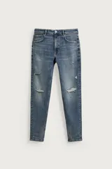 Jeans skinny fit de color azul, con efecto lavado y detalles de roturas en las piernas. Diseño de cinco bolsillos, tiro medio y cierre frontal con cremallera y botón.