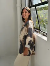 Sweater de punto con diseño estampado tipo animal print en tonos negro, marrón y beige. Presenta cuello en V, mangas tres cuartos con dobladillo y un corte holgado.