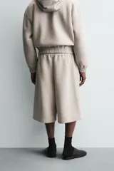 Bermuda de corte oversize confeccionada en tejido técnico compacto con elasticidad. Presenta cintura elástica ajustable con cordón, pinzas en el delantero y la espalda, y bolsillos laterales.