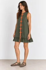 Vestido corto sin mangas color verde militar con ribetes y alamares en color naranja, cuello mao, cierre frontal con botones y volado en el ruedo.