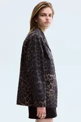 Campera de sarga de algodón con estampado animal print, cuello abierto, cierre frontal con botones y bolsillos delanteros de parche con solapa. Presenta hombros levemente caídos y puños abotonados.