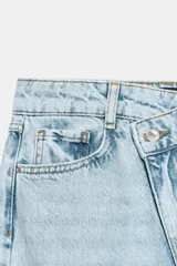 Jeans de tiro alto con diseño de cintura cruzada, cinco bolsillos y pernera recta con bajo sin costura. Cierre frontal con cremallera y botones.