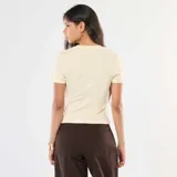 Camiseta color beige de punto de canalé fino, con cuello redondo y mangas cortas.