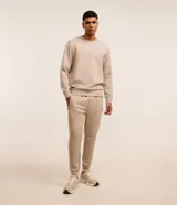 Pantalón jogger deportivo color beige, de cintura elástica, bolsillos laterales con cremallera y puños ajustados en los tobillos.