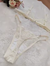 Conjunto de lencería de encaje color champagne, compuesto por un bralette triangular sin aro y una bombacha tipo tanga con tiras laterales ajustables.