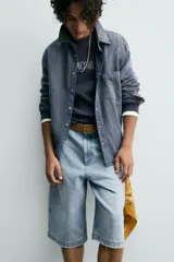 Bermuda de denim de algodón, color celeste claro lavado, de corte ancho (relaxed fit) y largo hasta la rodilla. Presenta cierre frontal con botón y cremallera, bolsillos delanteros y bolsillos traseros de plastrón.