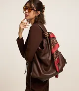 Bolso hobo grande de color marrón, con diseño desestructurado, asas dobles, cierre superior y cierres laterales ajustables.