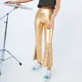 Pantalón de cuero sintético metalizado color dorado, de corte ajustado en la parte superior y botamanga acampanada con aberturas frontales decoradas con tachas.