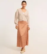 Cardigan corto de punto color beige claro, con escote en V, manga larga abullonada y cierre frontal de botones. Posee bolsillos delanteros tipo parche.