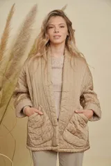 Campera tipo kimono acolchada en color beige, con diseño de costuras verticales, mangas largas con puños vueltos y bolsillos frontales amplios.