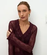 Blusa de encaje transparente color bordó, con mangas largas, escote en V con volados frontales y bajo fruncido.