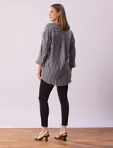 Blusa de poliéster con estampado de rayas verticales, cuello en V con botones, mangas tres cuartos y tajos laterales.