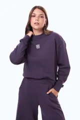 Buzo de felpa color violeta oscuro, con cuello redondo, mangas largas con puños acanalados y un pequeño parche cuadrado con diseño de tablero de ajedrez en el centro del pecho.
