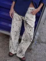 Jean de tiro medio y silueta recta levemente acampanada, con estampado tipo cowhide print. Cuenta con cierre frontal, botón y bolsillos funcionales.