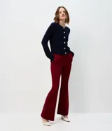Cárdigan de punto trenzado color marrón, con cuello redondo, manga larga y cierre frontal con botones metálicos. Presenta puños y ruedo acanalados.