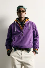 Chaqueta canguro técnica de corte relaxed fit en color violeta, con cuello subido ajustable, cierre frontal de cremallera parcial, manga larga y bolsillos frontales con cierre y tipo canguro.