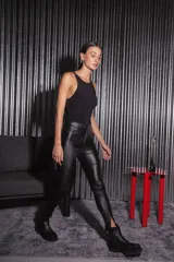 Pantalón negro de bengalina engomada, tiro alto, con cierre metálico frontal y corte en la botamanga.