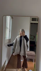 Ruana tejida a mano en lana merino, color gris, con diseño de textura en la parte inferior y terminación con flecos.