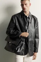 Bolso de mano y hombro color negro, con diseño estructurado, solapa frontal y cierre metálico. Cuenta con asa superior de mano y un compartimento principal amplio.