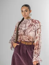 Camisa de seda italiana con diseño reversible, permitiendo usar el lazo en la parte frontal o posterior. Presenta un estampado sutil con motivos abstractos y animal print, cuello alto con volados, mangas largas con puños elásticos y corte holgado.