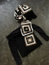 Bufanda tejida a mano en crochet, con capucha y diseño de cuadrados en tonos beige, marrón y negro.