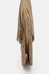 Bolso de hombro tipo shopper confeccionado en serraje, con diseño de doble capa de flecos largos en el cuerpo. Cuenta con asa de hombro integrada, cierre mediante botón imantado y bolsillo interior con cremallera.