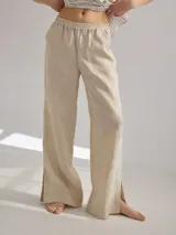 Pantalon de corte recto y tiro medio, confeccionado en lino, con cintura elastizada y tajos laterales en el ruedo.