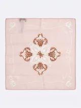 Pañuelo cuadrado tipo bandana con diseño estampado central en tonos marrón y crudo sobre fondo rosa.