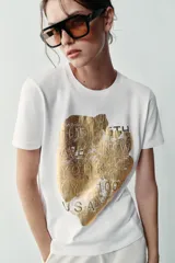 Camiseta blanca de manga corta y cuello redondo, con detalle de estampa central metalizada de efecto texturizado y diseño regular fit.