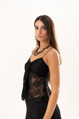 Top de encaje negro con breteles finos, escote con detalle de nudo frontal y diseño con apertura central.