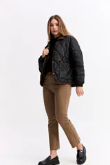 Campera matelaseada de diseño en rombos color verde oliva, con cuello y bordes en contraste color marrón. Presenta cierre frontal con botones a presión, mangas largas con puños elásticos y corte holgado.