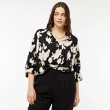 Blusa de manga larga con cuello en V, confeccionada en tejido ligero con estampado floral en blanco y negro.